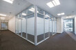 © alhim - An empty bright office room with brown carpet and a study with glass walls.