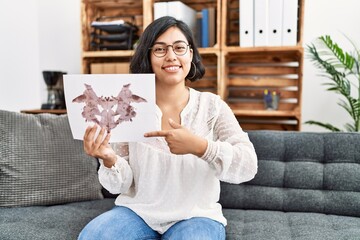 Poster - Young hispanic therapist woman holding rorschach test smiling happy pointing with hand and finger