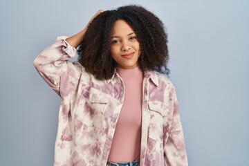 Poster - Young african american woman standing over blue background confuse and wonder about question. uncertain with doubt, thinking with hand on head. pensive concept.