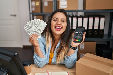 Sticker - Young hispanic woman working at small business ecommerce holding money and dataphone smiling and laughing hard out loud because funny crazy joke.