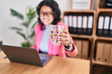 Wall Mural - Young latin woman business worker using touchpad drinking water at office