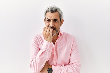 Sticker - Middle age hispanic man standing over isolated background looking stressed and nervous with hands on mouth biting nails. anxiety problem.