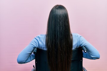 Wall Mural - Beautiful woman with blue eyes sitting on wheelchair standing backwards looking away with arms on body