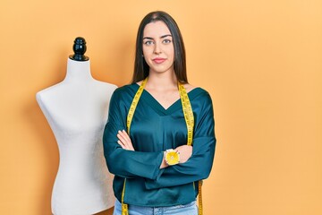 Poster - Beautiful woman with blue eyes standing by manikin with crossed arms relaxed with serious expression on face. simple and natural looking at the camera.