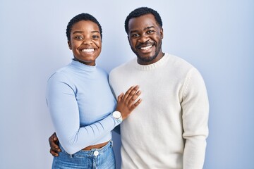 Canvas Print - Young african american couple standing over blue background with a happy and cool smile on face. lucky person.