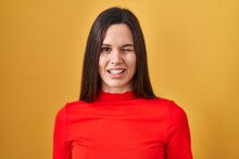 Young Hispanic Woman Standing Over Yellow Background Winking Looking At The Camera With Sexy Expression, Cheerful And Happy Face.