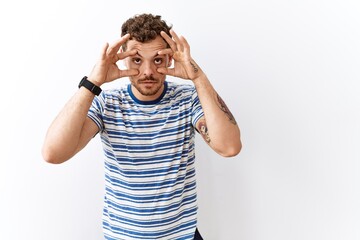 Sticker - Handsome young man standing over isolated background trying to open eyes with fingers, sleepy and tired for morning fatigue