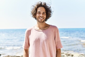 Canvas Print - Young hispanic man smiling happy standing at the beach.