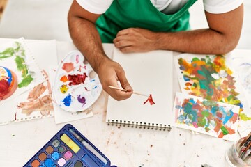 Wall Mural - Young hispanic man drawing on notebook at art studio