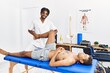 Two men physiptherapist and patient having rehab session stretching leg at clinic
