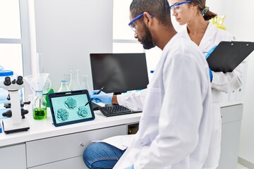 Wall Mural - Man and woman scientist partners looking embryo image on touchpad at laboratory