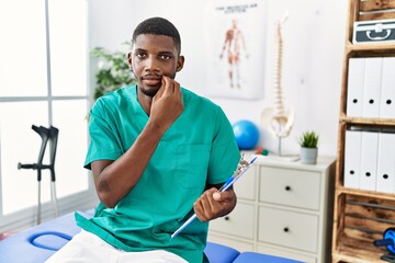 Canvas Print - Young african american man working at pain recovery clinic mouth and lips shut as zip with fingers. secret and silent, taboo talking