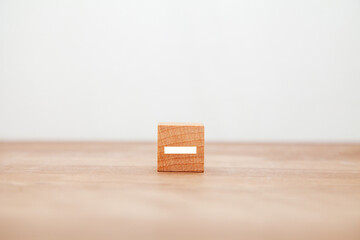 -の文字。マイナス。減法。減る。木製ブロックに書かれている。白い文字。木製テーブルの背景。