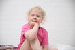blond little girl sits on the bed with her hand under her cheek, baby sleep