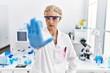 © Krakenimages.com - Middle age blonde woman working at scientist laboratory doing stop sing with palm of the hand. warning expression with negative and serious gesture on the face.