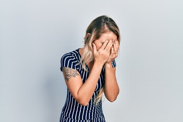 Sticker - Beautiful young blonde woman wearing casual striped dress with sad expression covering face with hands while crying. depression concept.