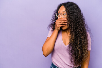 Wall Mural - Young hispanic woman isolated on purple background thoughtful looking to a copy space covering mouth with hand.