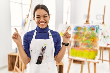 Canvas Print - Young brunette woman at art studio smiling confident pointing with fingers to different directions. copy space for advertisement