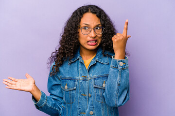 Wall Mural - Young hispanic woman isolated on purple background holding and showing a product on hand.