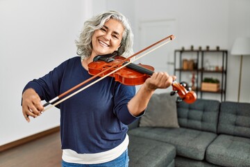 Poster - Middle age grey-haired artist woman playing violin standing at home.