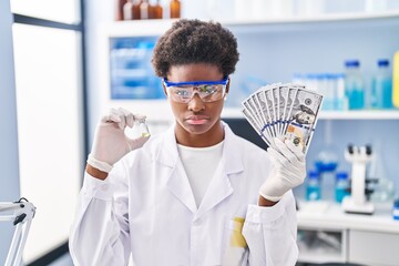 Poster - African american woman working at scientist laboratory holding dollars depressed and worry for distress, crying angry and afraid. sad expression.