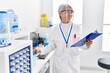 © Krakenimages.com - Middle age grey-haired woman wearing scientist uniform holding clipboard and test tube at laboratory