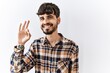 © Krakenimages.com - Hispanic man with beard standing over isolated background smiling positive doing ok sign with hand and fingers. successful expression.