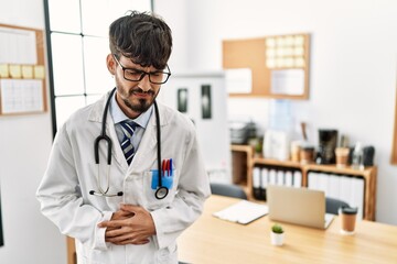 Poster - Hispanic man with beard wearing doctor uniform and stethoscope at the office with hand on stomach because nausea, painful disease feeling unwell. ache concept.