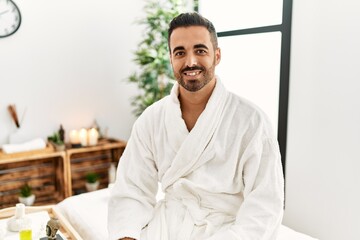 Canvas Print - Young hispanic man smiling confident wearing bathrobe at beauty center