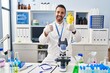 © Krakenimages.com - Young hispanic man with beard working at scientist laboratory success sign doing positive gesture with hand, thumbs up smiling and happy. cheerful expression and winner gesture.