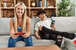 © Krakenimages.com - Young couple smiling happy playing video game and using smartphone at home.
