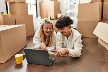 Poster - Young beautiul couple using laptop choosing painting color at new home.