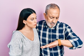 Canvas Print - Hispanic father and daughter wearing casual clothes checking the time on wrist watch, relaxed and confident