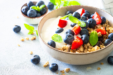 Wall Mural - Greek Yogurt with granola and fresh berries at white table.