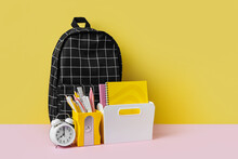 Black Plaid Backpack With School Stationery On Yellow And Pink Background. Office Supplies With School Bag On The Table. Concept Back To School.