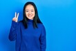 Young chinese girl wearing casual clothes showing and pointing up with fingers number two while smiling confident and happy.
