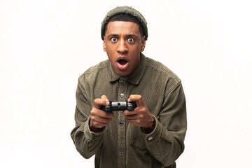 Excited young multiracial man playing video games and looking at camera with surprised face, holding wireless joystick console isolated over white background. Gamer concept