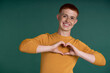 © gpointstudio - Happy young redhead man showing heart shape made with hands