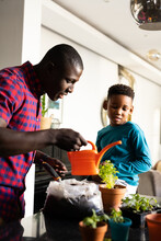 Image Of Smiling African American Boy With Father Watering Plant