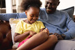 © Wavebreak Media - Image of happy african american father and daughter sitting on sofa with tablet