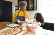© WavebreakMediaMicro - Image of happy african american grandmother and granddaughter baking in kitchen