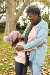 Wall Mural - Vertical image of happy african american grandmother and granddaughter embracing in garden