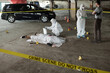 © pressmaster - Criminological expert in coveralls, mask, gloves and overboots communicating with policeman on crime scene