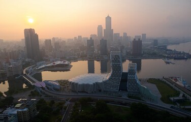 Wall Mural - Aerial view of Downtown Kaohsiung at sunrise, a vibrant seaport city in South Taiwan, with the landmark 85 Sky Tower standing by the harbor and the golden sun rising under dramatic twilight sky