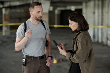 Wall Mural - Confident detective inspector and his female colleague discussing evidences or circumstances of murder during crime scene investigation