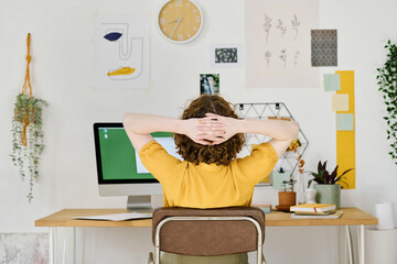 Aufkleber - Rear view of young freelance designer having minute of rest while sitting in front of computer monitor and keeping hands behind head