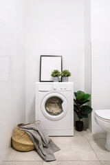 Wall Mural - Loaded washing machine standing in white tiled bathroom