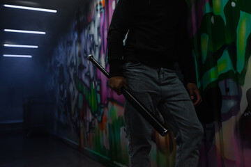 Wall Mural - Cropped view of african american bandit holding baseball bat near graffiti on wall in garage