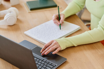 Aufkleber - Young female student making notes in copybook while looking through online data during work over new school project in front of laptop
