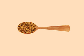 Wall Mural - Fenugreek seeds in wooden spoon. Top view, copy space. Healthy seeds of plant Trigonella foenum-graecum. Used in culinary and medicine